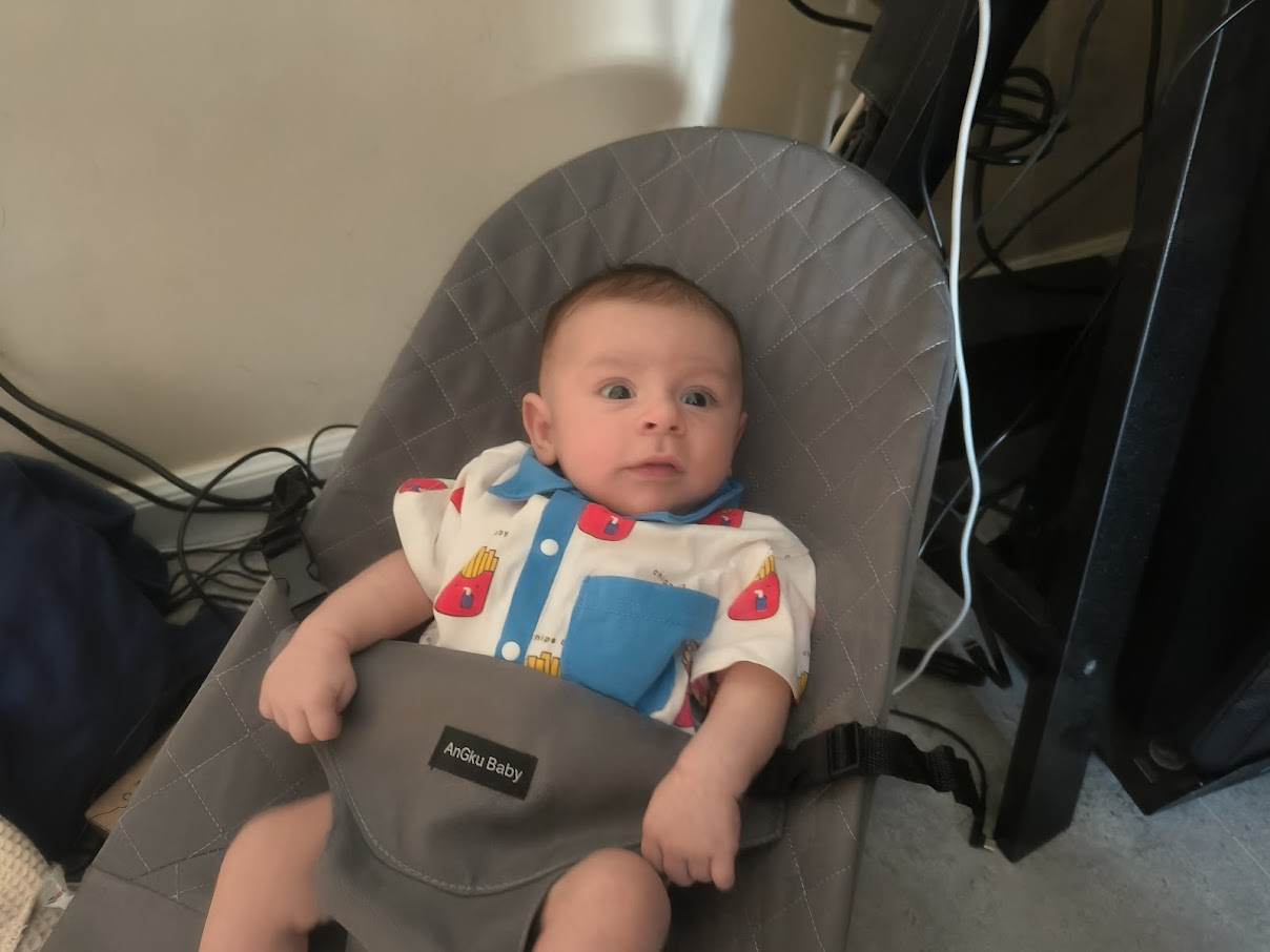 Ezra sitting in gray Anotu Baby bouncer chair